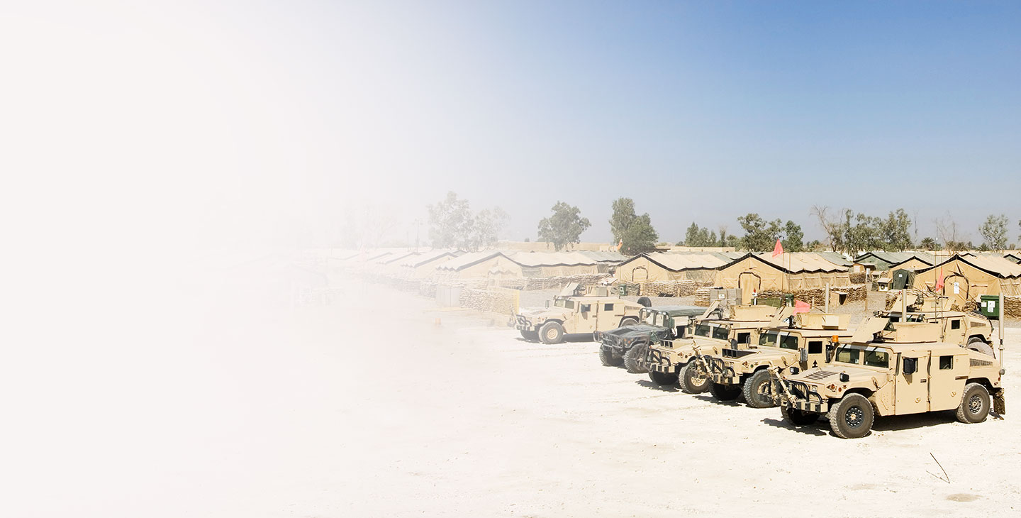 Five humvees parked in front of several army tents
