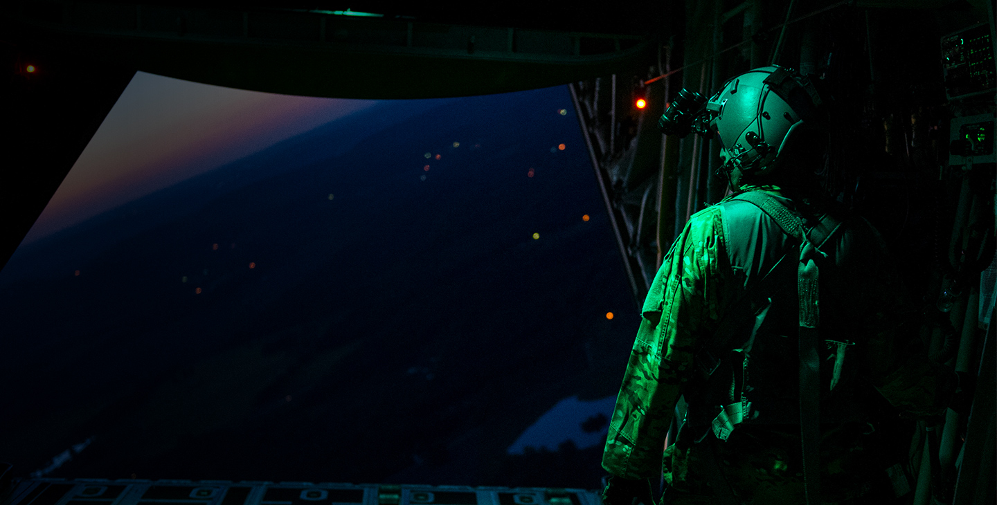 Soldier with a headset using military satcom to communicate, looking out of an aircraft at night